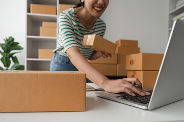 Starting a Small Business SME Owner Female check orders online to prepare to pack boxes of goods...
