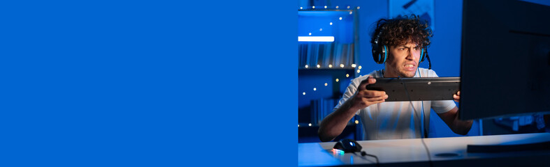 Arab gamer gets angry at night with his keyboard and shouts. Guy is angry at loss in virtual game, break the keyboard. Copy space © Andrii Lysenko