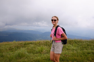 Woman is hiking in mountains in summer.Beautiful mountain landscape in Carpathians, Romania.Travel and tourism.Woman hiker is enjoying the mountain view.