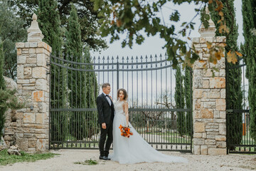 Happy stylish smiling couple walking in Tuscany, Italy on their wedding day. The bride and groom walk down the street by the hands. A stylish young couple walks. Husband and wife communicate nicely