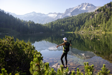 A young woman with backpack staying at the mountain lake after hike in the Austrian Alps