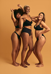 Cheerful diverse women in underwear standing close in studio