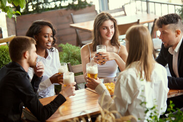 Young business people, colleagues meeting together at cafe, bar after work to drink beer, talk and spend relaxing time. Concept of leisure time, business, communication, fun, alcohol drink