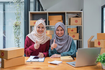 two muslim woman thumbs up working online sales of they made at home. small business muslim selling online