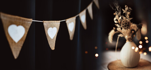 Hanging outdoor party string with floral decoration in boho style and golden lights. Summer night background for wedding and holidays.