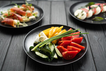 Party table setting with various veggie snacks and vegetarian starters on dark background.
