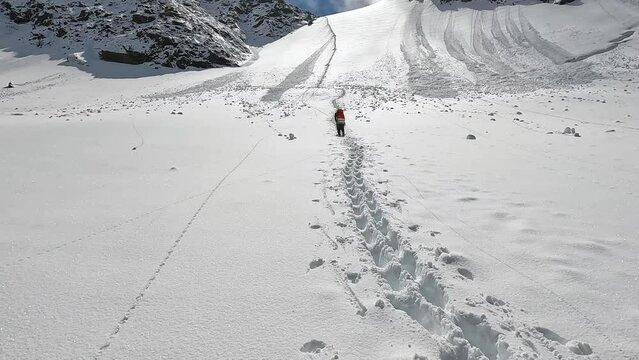 A male climber approaches the Delaunay Pass along a snowy trail. Majestic mountains, ridges and rocks. Climbing Belukha. Beautiful nature of Altai, Russia.