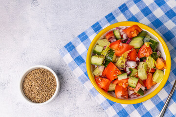 Kachumber Salad is the Indian cucumber, tomato, and onion salad, top view. This is a fresh, easy chopped salad with cumin or cumin seeds. The vegetables are dressed with lemon juice and salt.