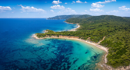 Panoramic aerial view of the beach at Mantraki, Skiathos island, Sporades, Greece, with lush pine tree forest and emerald sea