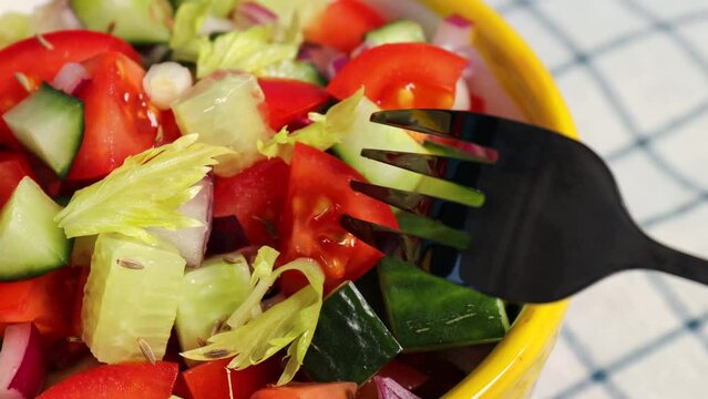 Kachumber Salad is the Indian cucumber, tomato, and onion salad. The girl is stabbing a salad with cumin seeds with a fork, a fresh, easy chopped salad. The vegetables are dressed with lemon juice and