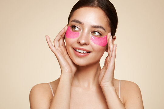 A young beautiful smiling woman with cosmetic patches on her eyes. Cosmetic procedures skin care around the eyes. Perfect healthy facial skin