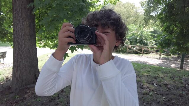 Boy kid 9 years old taking pictures photos with camera in a park during the holidays - travelling and learn to take pictures in childhood