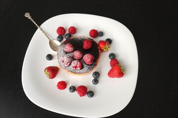 cream cake with raspberries and blueberries and small macaroons served on a large white plate