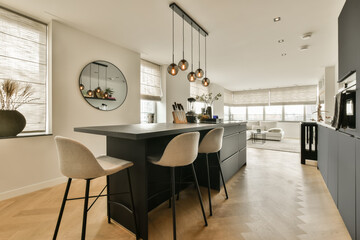 a kitchen and dining area in a modern apartment with wood flooring, white walls and black cabinetd cabinets