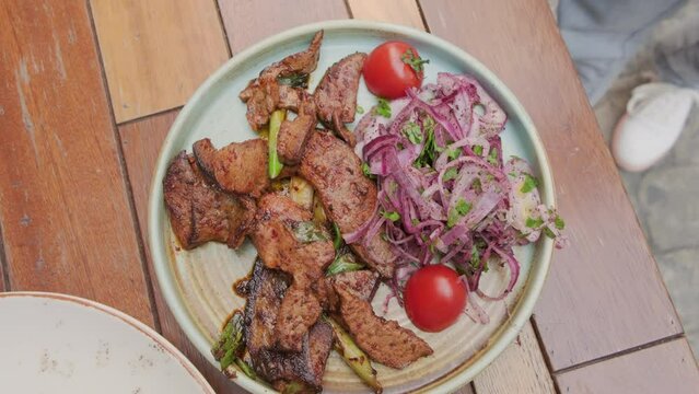 Serving liver leaf dish in street cafe for lunch or dinner. Middle Eastern lamb liver and parsley onion salad.