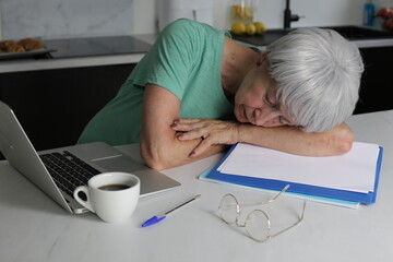 Senior woman falling sleep while doing some home office work 