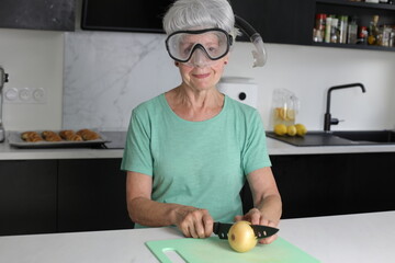 Senior woman chopping onions with scuba mask 