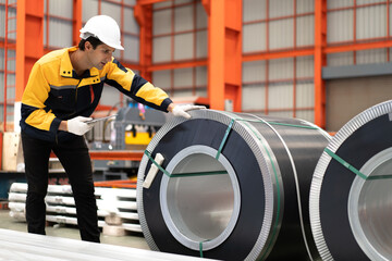 Latin engineer wears safety helmet work in heavy metal engineering factory. Young male hispanic worker wears white hard hat checking product materials equipment in metalwork manufacturing facility