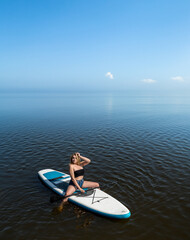 pretty girl in summer time resting on sup board on the water