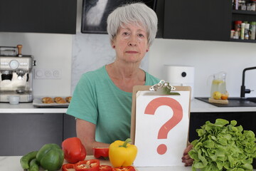 Senior woman holding question mark in the kitchen