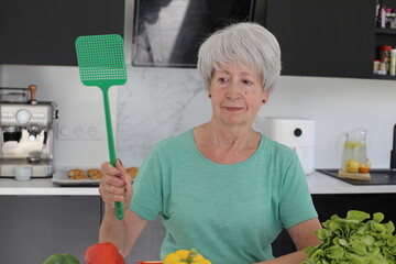 Senior woman trying to catch a fly 