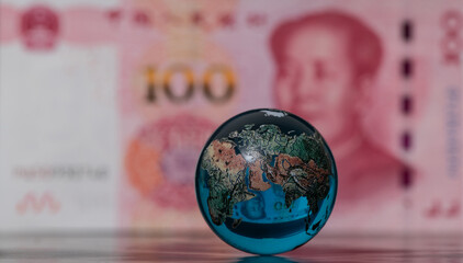 Glass globe in front of a 100 Chinese yuan banknote