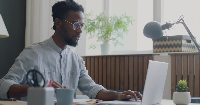 Side view of employee working with laptop concentrated on office work sitting at desk against window background. People and job concept.