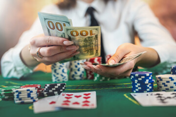 female player counts chips for money and raises bet while playing poker in casino.