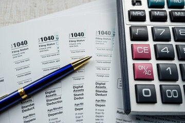 1040 tax form with pen and calcultor on desk, paperwork