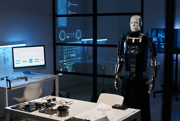 Robot from metal standing in modern laboratory with computer and computer details