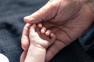 Hands of senior person and little baby close up.