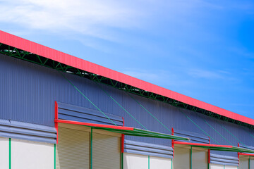 Automatic roller shutter doors with awning of modern rental warehouse building against blue sky background, perspective side view