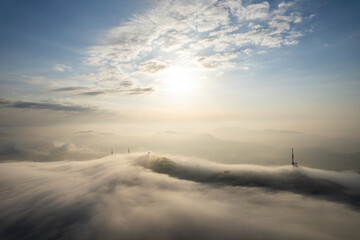 Aerial view of mountain peak against sky surrounded by fog during sunrise