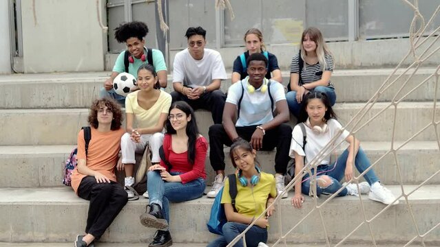 Group of teenage multiethnic students sitting on a high school stairs looking at camera