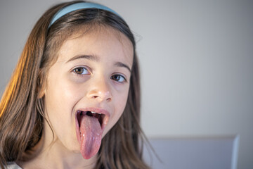 A child girl open her mouth and show her tounge.