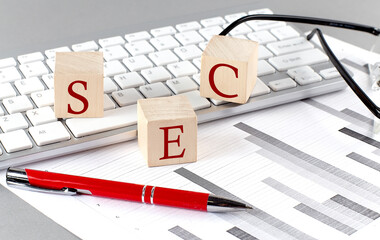 SEC written on a wooden cube on the keyboard with chart on grey background