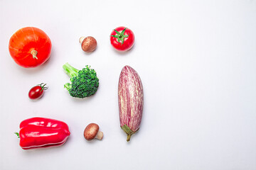 Creative arrangement of pumpkin, eggplant, bell pepper, sherry tomato, tomato, broccoli and mushrooms on a white background. Food concept. Healthy food. View from above.