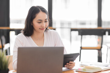 Obraz premium Young asian woman using laptop computer for business studying, watch online virtual webinar training meeting, video call. Focused asian woman or Latin business woman work in office, copy space. 