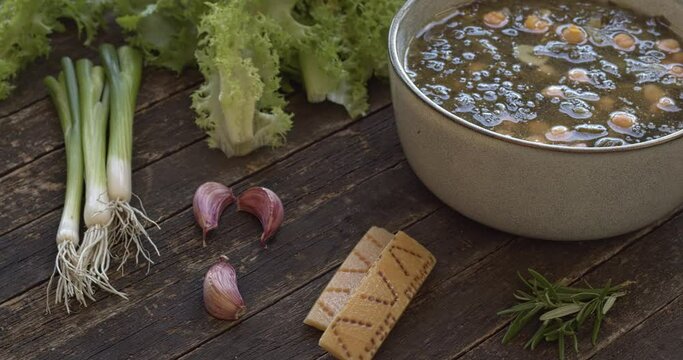 Curly endive and chickpea soup. Main ingredients shown: curly endive, garlic, Parmesan rind, scallions. Italian cuisine. Table spin. 