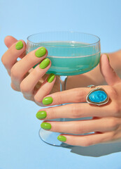 Beautiful womans hand with summer green nail design holding glass. Manicure, pedicure beauty salon concept