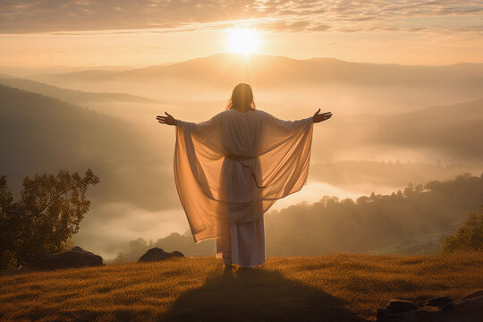 Rear view of Jesus Christ raised hands and praying to god with a sunrise sky background.