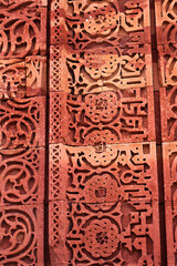 Fototapeta na wymiar Close-up of Qutb Minar fresco and motifs on tower wall. Wall Detail from Qutub Minar monument in Delhi, India or Ancient carved red sandstone background at the Qutb Minar medieval monuments