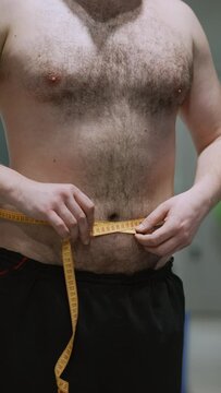 Young man measures his waist in the gym