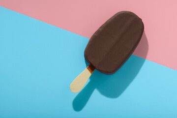 covered chocolate popsicle  with ice cream and hard shadow on blue, pink background, creative decoration of minimal summer concept