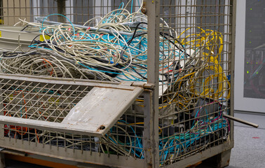 in the data center are old IT network cables and power cables stored in a lattice box for disposal - 624376798
