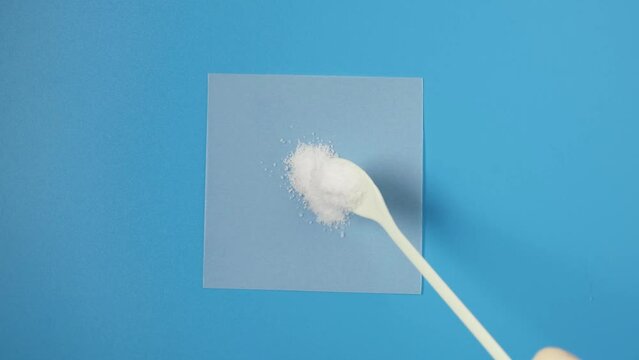 Sample of Dextrose monohydrate powder, d-Glucose or Grape sugar laid out with measuring spoon on paper. Natural sweetener, sugar substitute.