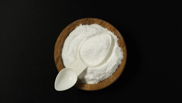 Dextrose monohydrate powder, d-Glucose or Grape sugar in wooden bowl with measuring spoon, top view.