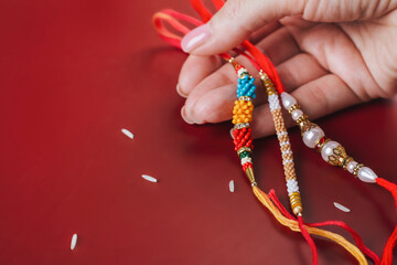 Raksha Bandhan background. Rakhi bracelets in female hand and rice grains. Traditional Indian Holiday Festival. Selective focus