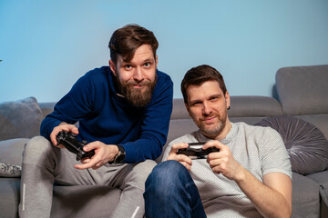 Two male best friends playing video games with joypad at home, night time © phoenix021