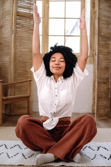 Woman with closed eyes and rised hands, practicing yoga